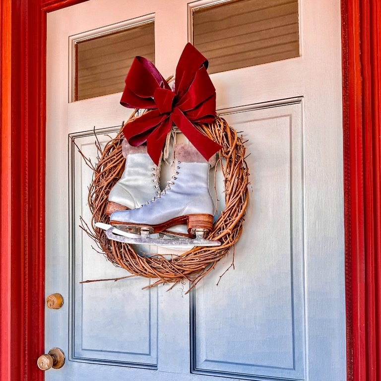 A festive wreath adorned with a pair of ice skates, perfect for 12 Days of Christmas Decorations.