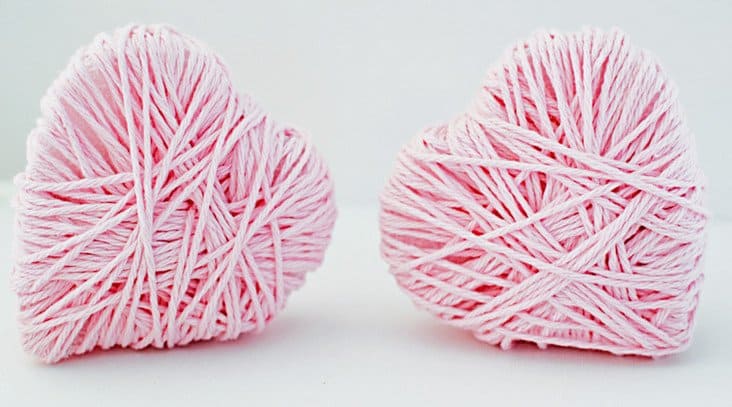 Two DIY pink hearts wrapped in pink yarn.