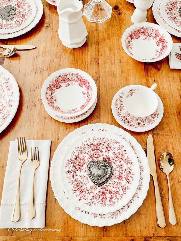 romantic table setting with collected vintage pink and white dishes on wood table.