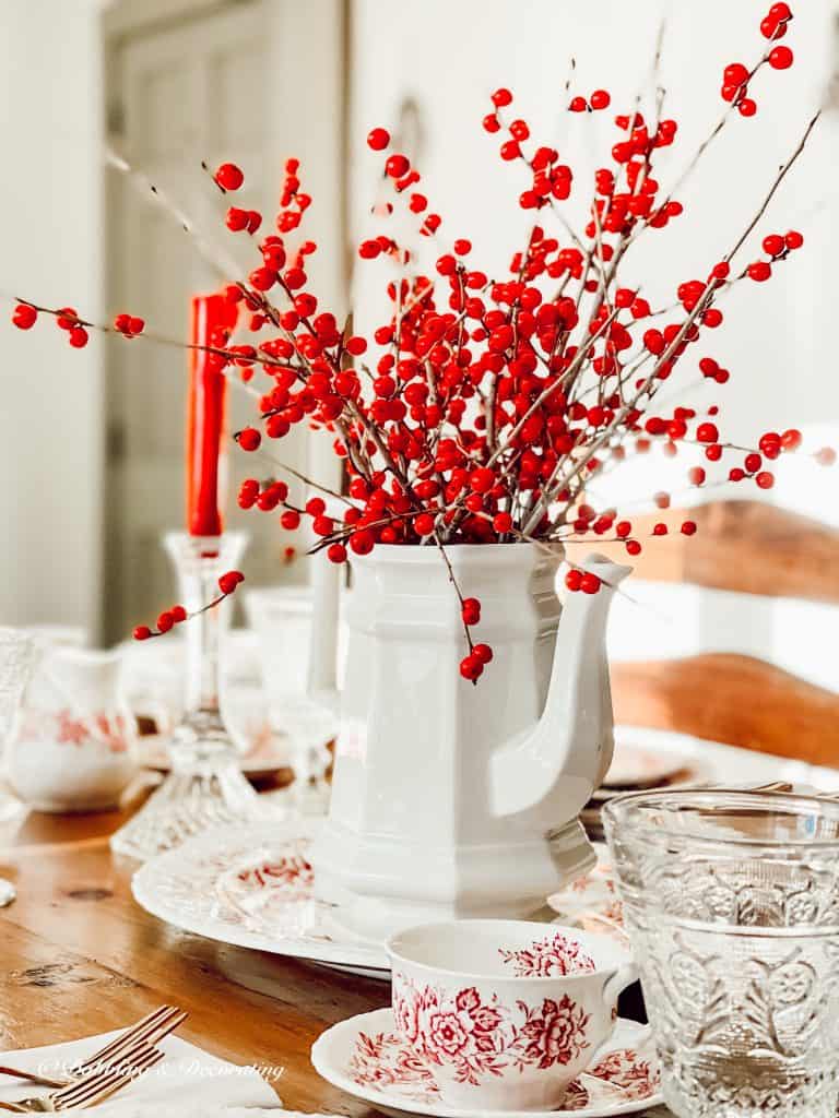 Winterberry centerpiece on romantic table setting with vintage white teapot and red candlesticks.