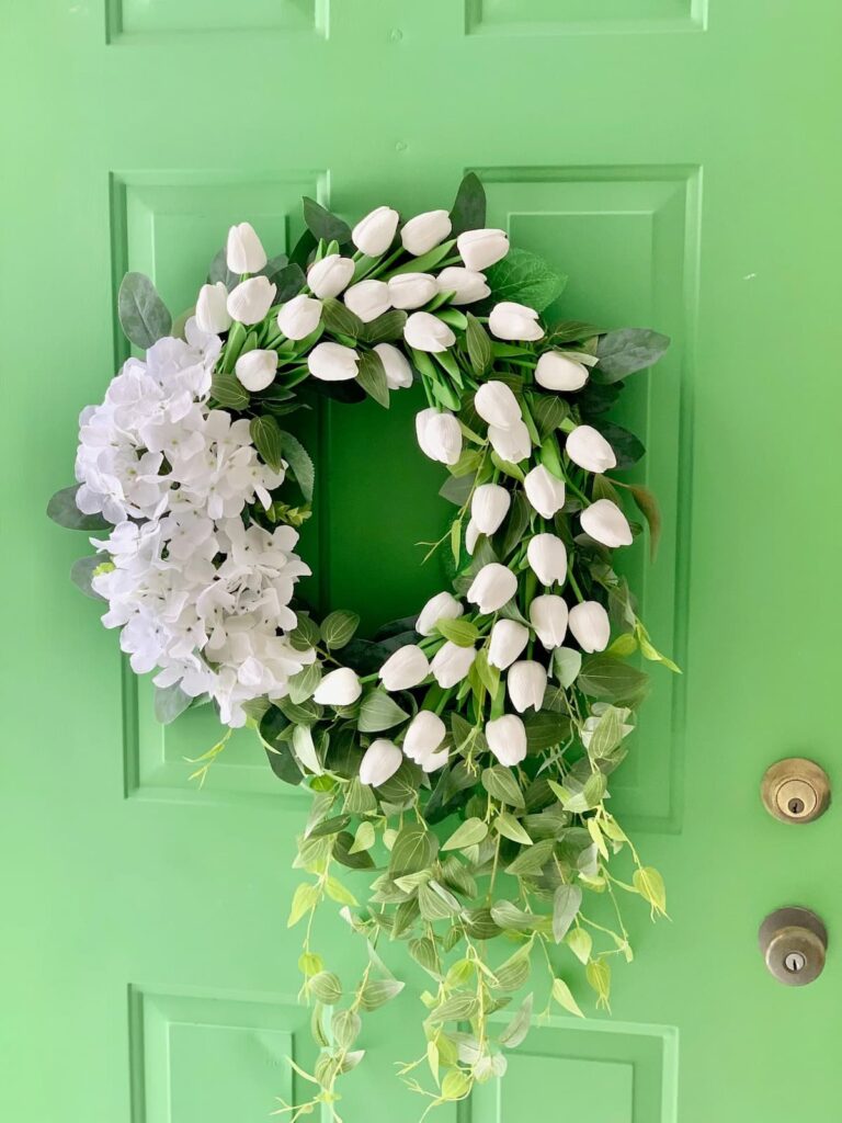 Summer and Spring wreath with white tulips and hydrangeas on a green door.