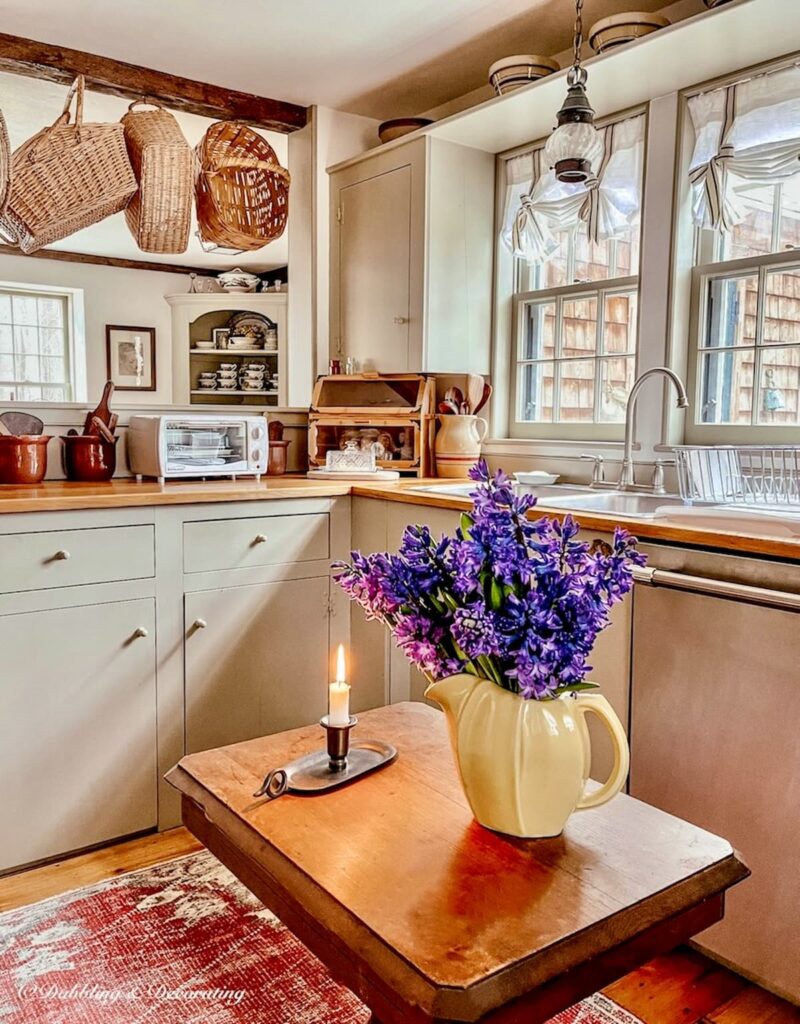 Colonial Style Kitchen with small kitchen table with yellow vase and purple flowers.