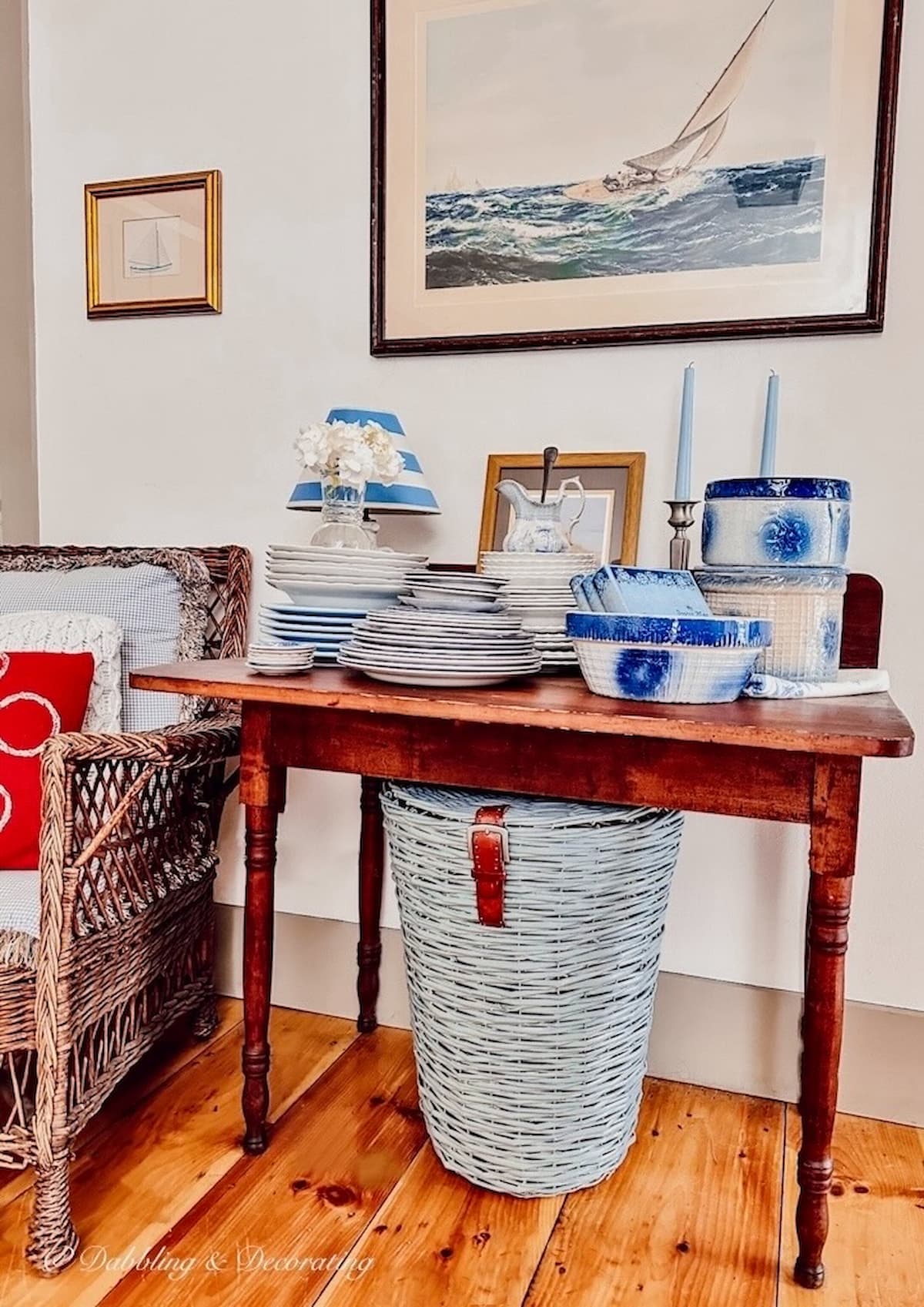 Blue basket under antique table topped with blue and white vintage dishes in a dining room nook.