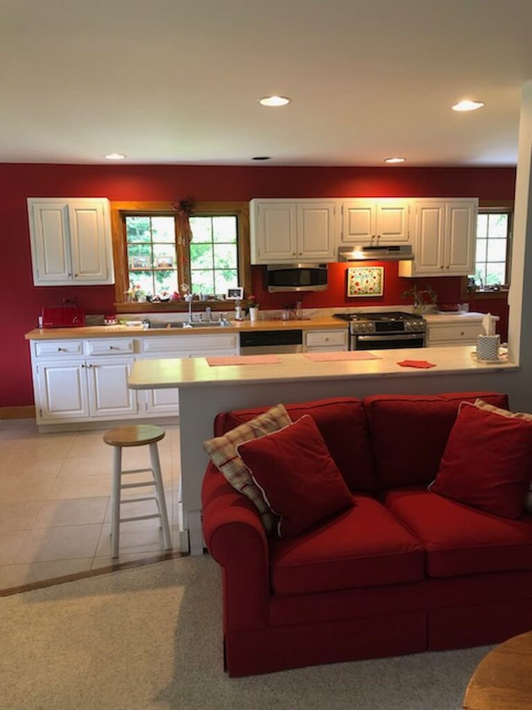 Red Wall kitchen with red couch and white cabinetry.