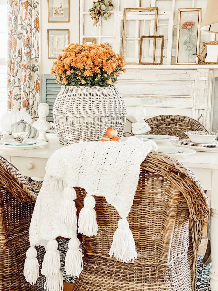 Antique white basket table centerpiece with orange Mums in vintage style dining room.