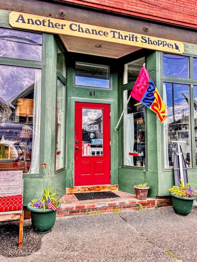 Another Chance Thrift Shoppe. Green shop with red door and open flag.