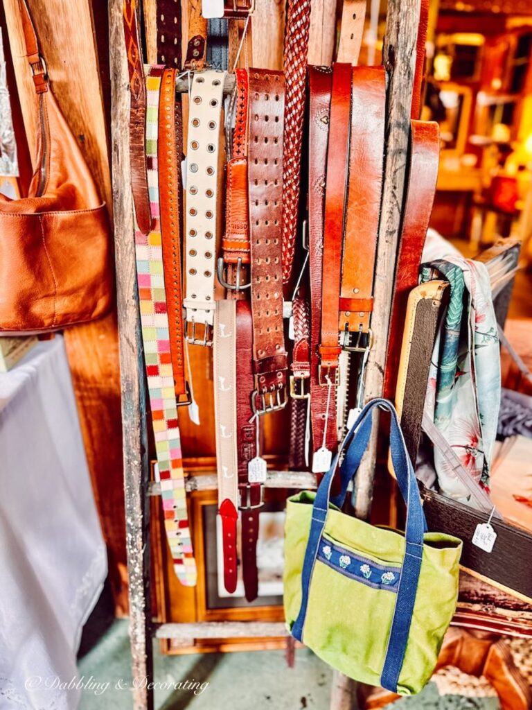 Leather belts hanging on a ladder.