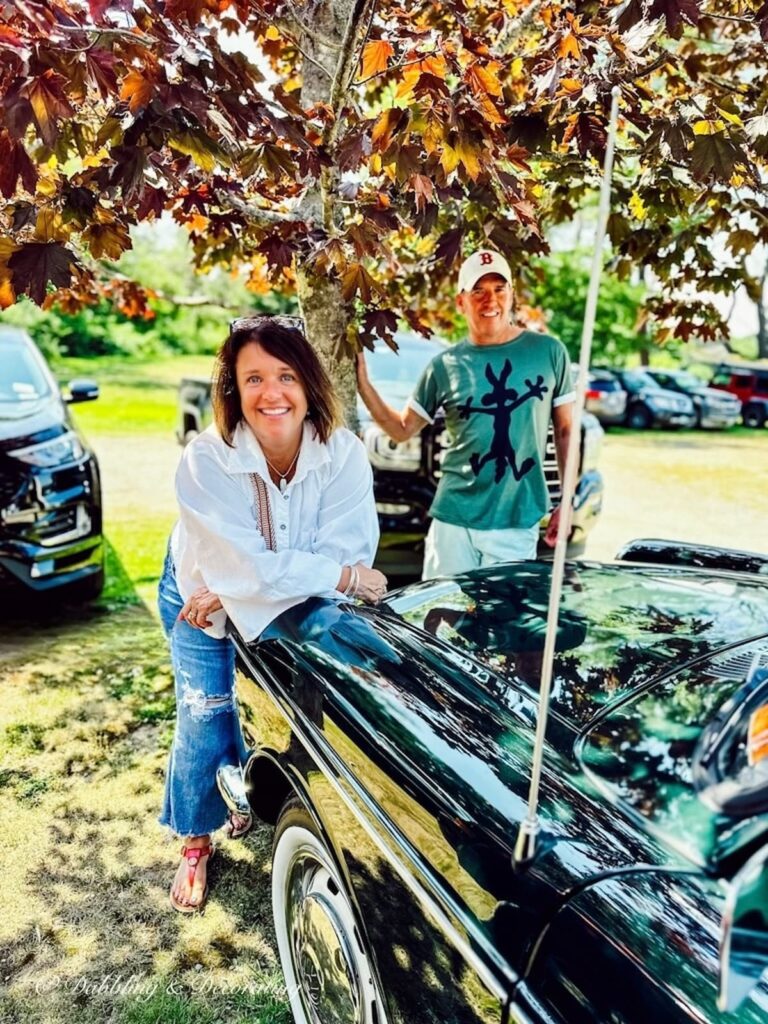 Girl leaning on vintage VW Fastback car and Man standing behind her.