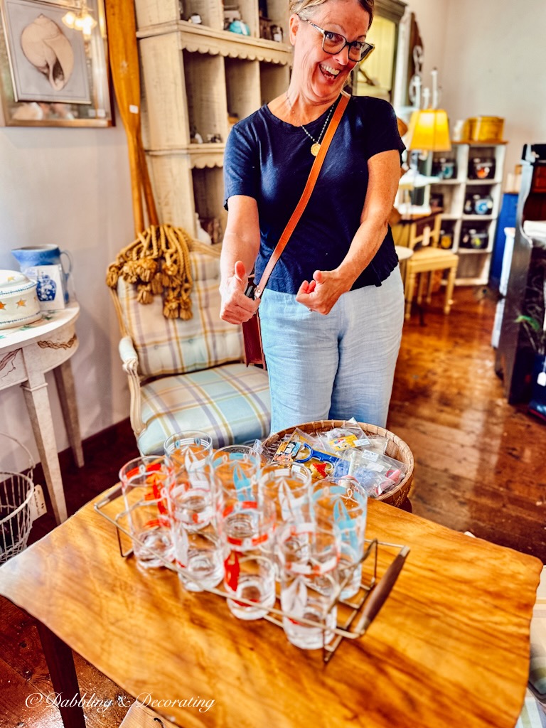 Woman thumbs up looking at glassware set at Sage Farm Antiques.