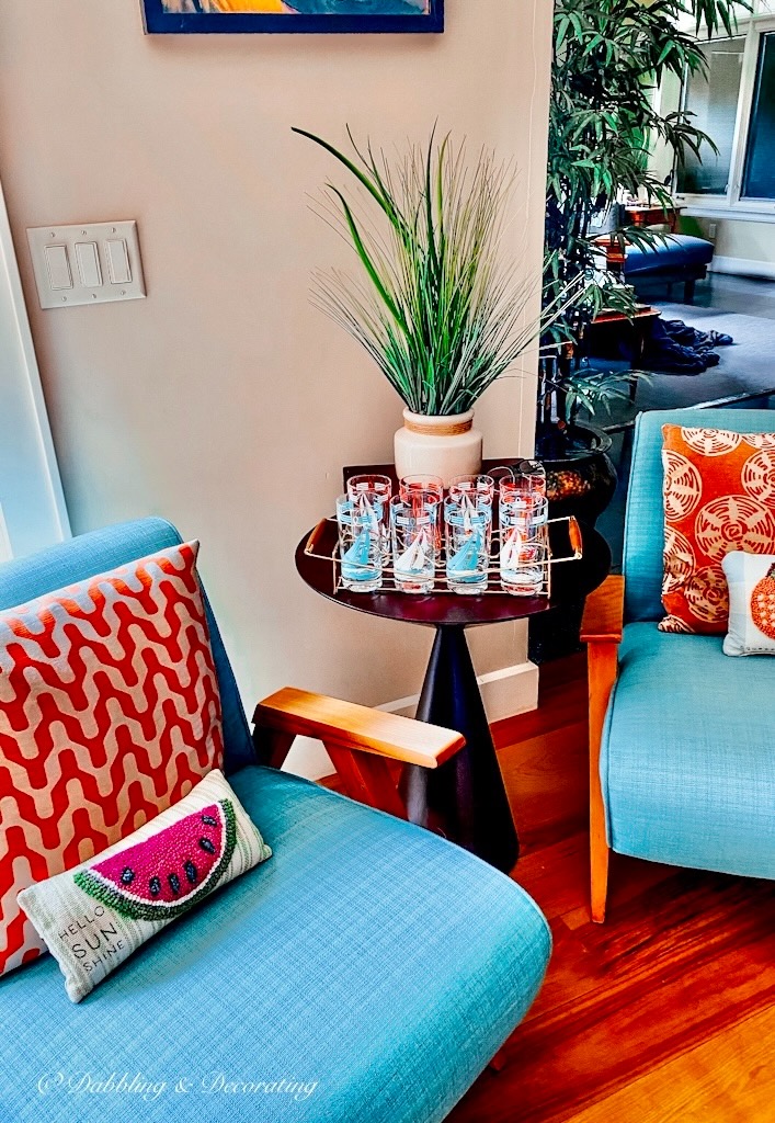 blue and orange modern retro decor with blue chair and vintage set of sailboat glassware on table.