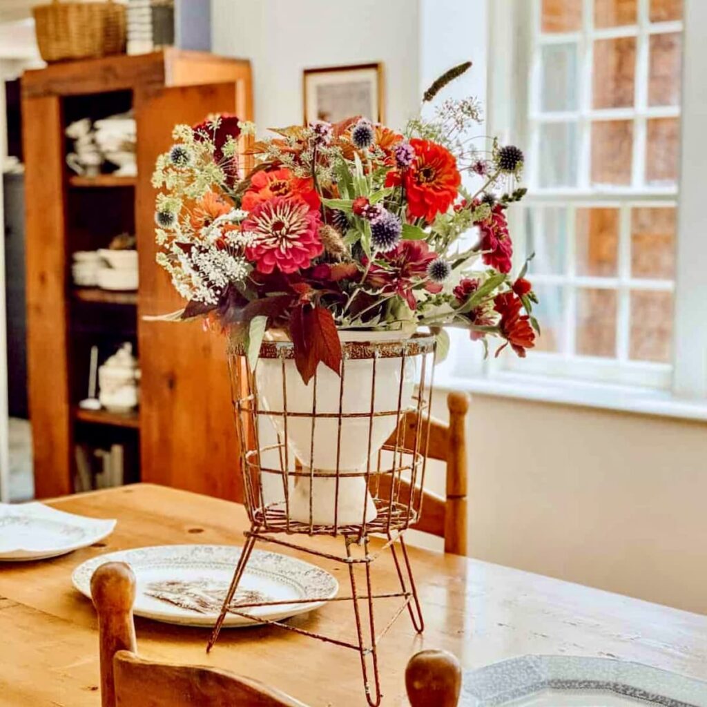 Antique wired basket with vintage floral centerpiece display on vintage pine dining room table.