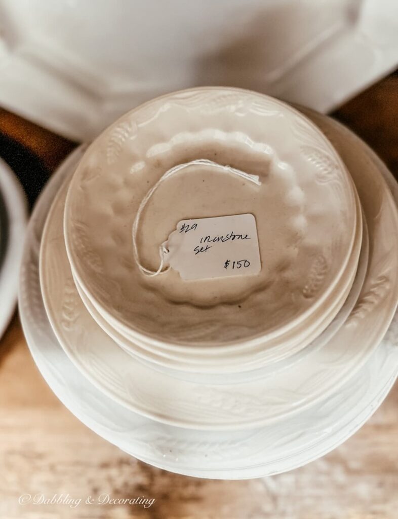 Stack of vintage white ironstone plates in antique shop.