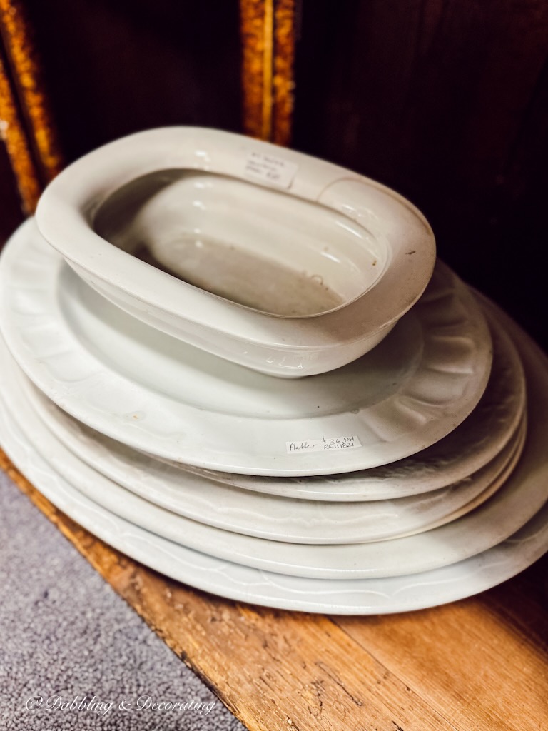 Stack of vintage white ironstone plates in antique shop.