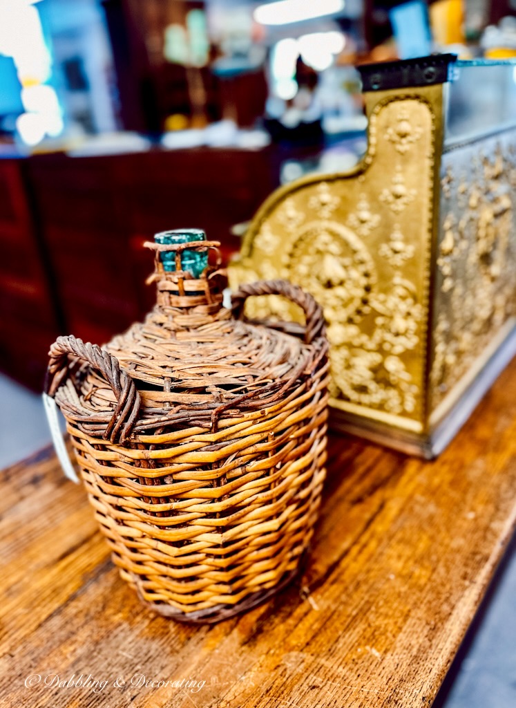 Vintage Demijohn at antique store check out counter with vintage gold cash register.