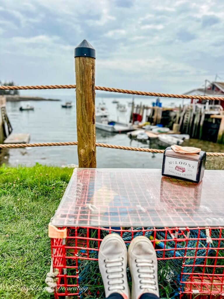 Lobster trap table with resting feet overlooking a coastal Maine fishing village.