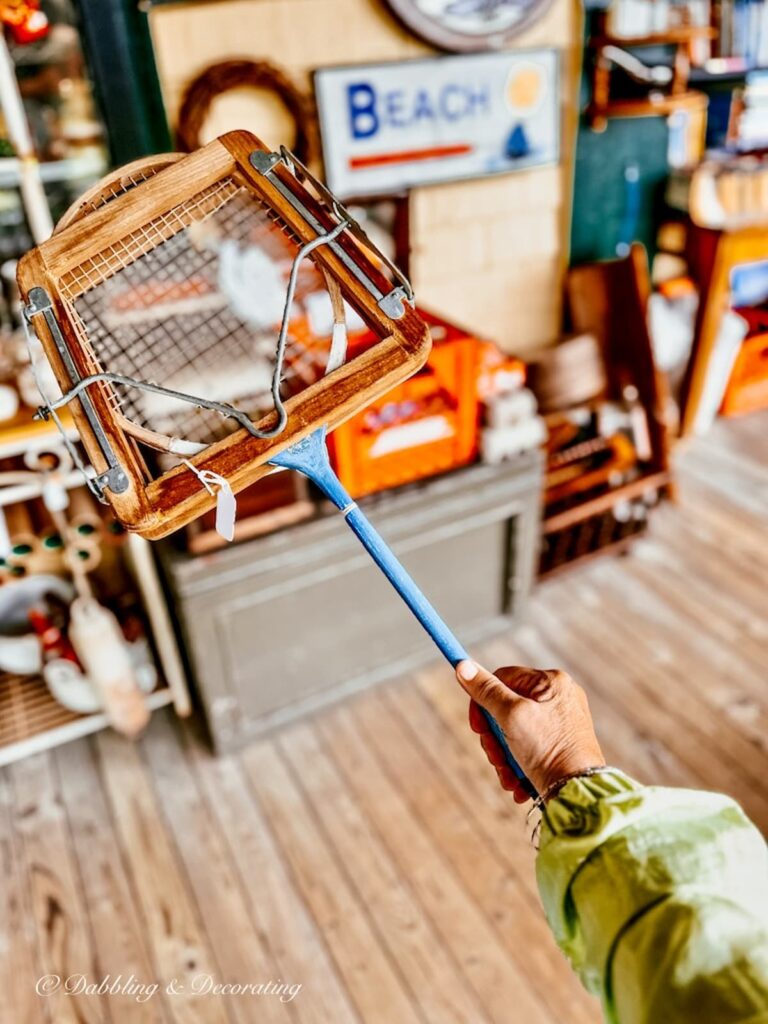 Vintage blue badminton racket with wooden press at antique store in hand.