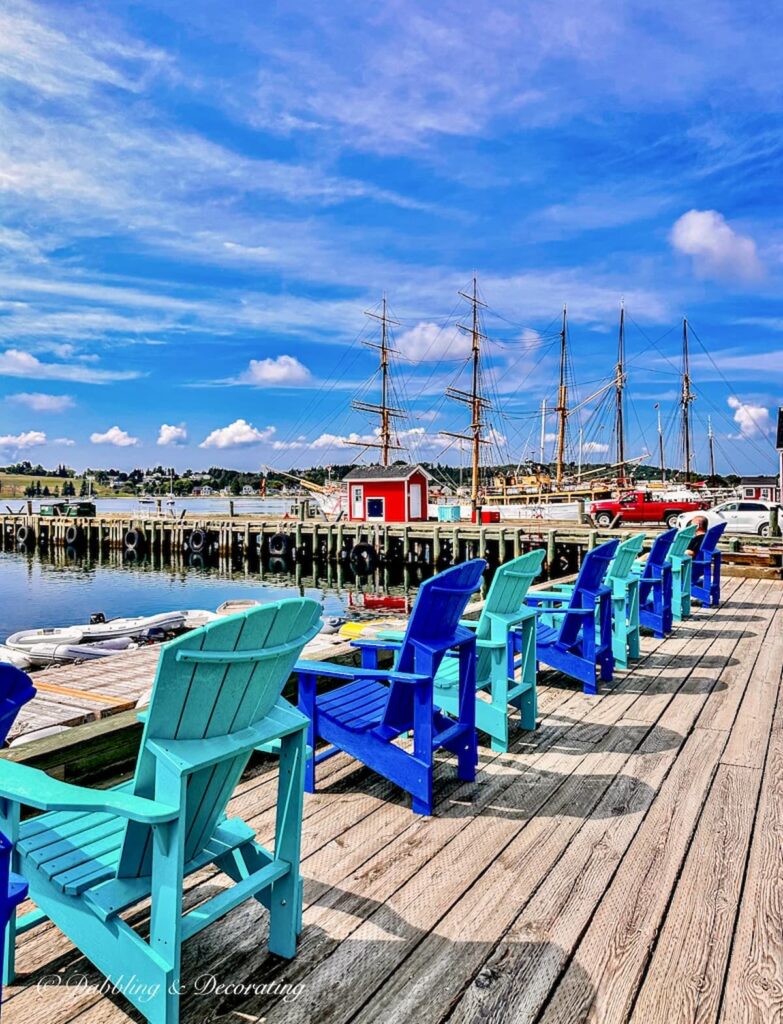 Lunenburg Nova Scotia waterfront with blue Adirondack chairs on harbor.