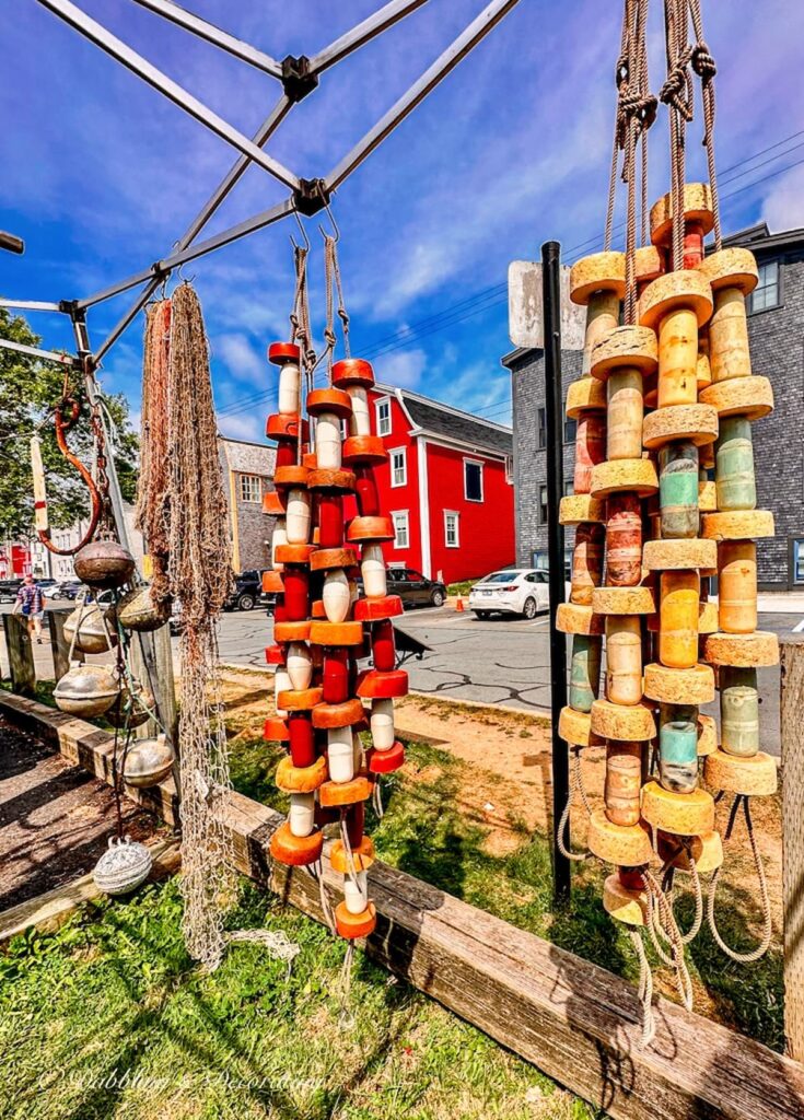 Lunenburg Nova Scotia hanging maritime fishing buoys next to red house on waterfront.