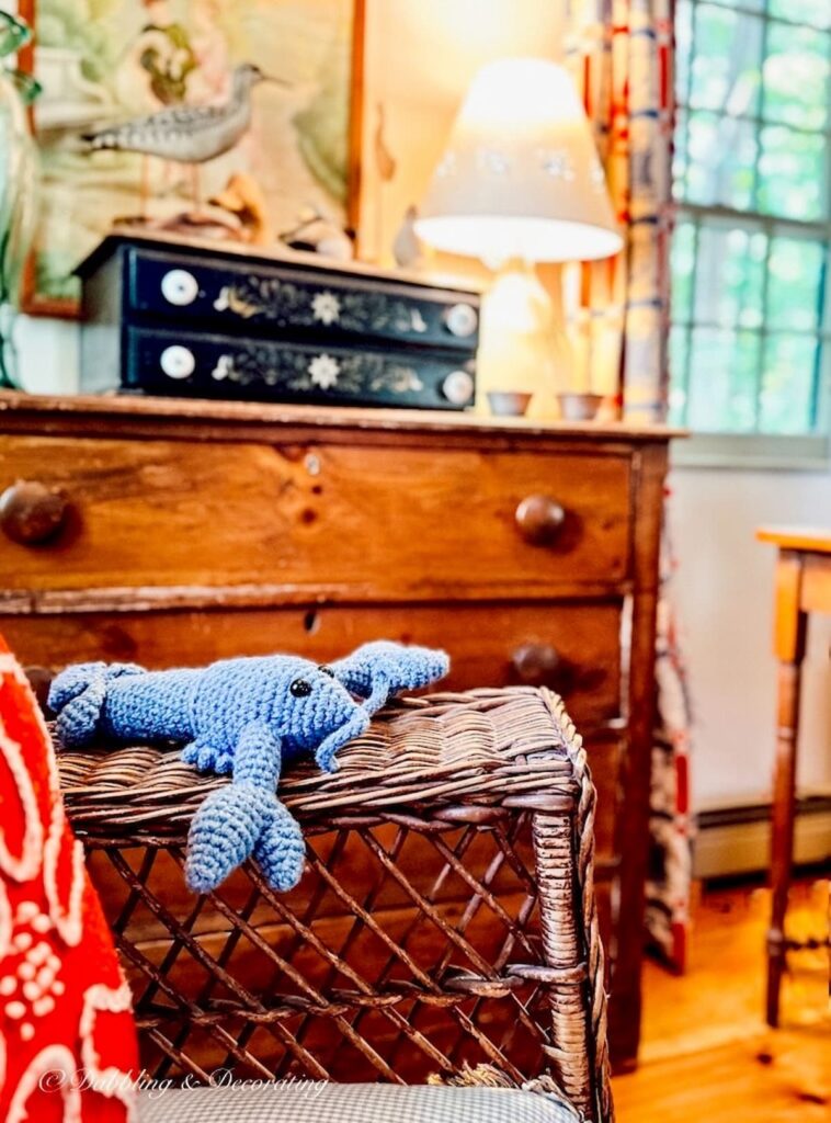 Blue handmade Lobster on wicker chair in vintage coastal living room.