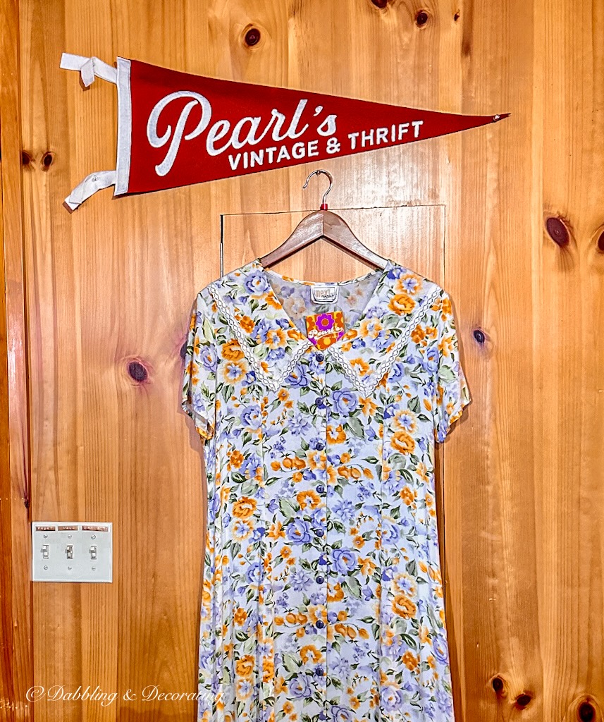 Pearl's Vintage & Thrift Banner hangin on wall over vintage dress in consignment shop.