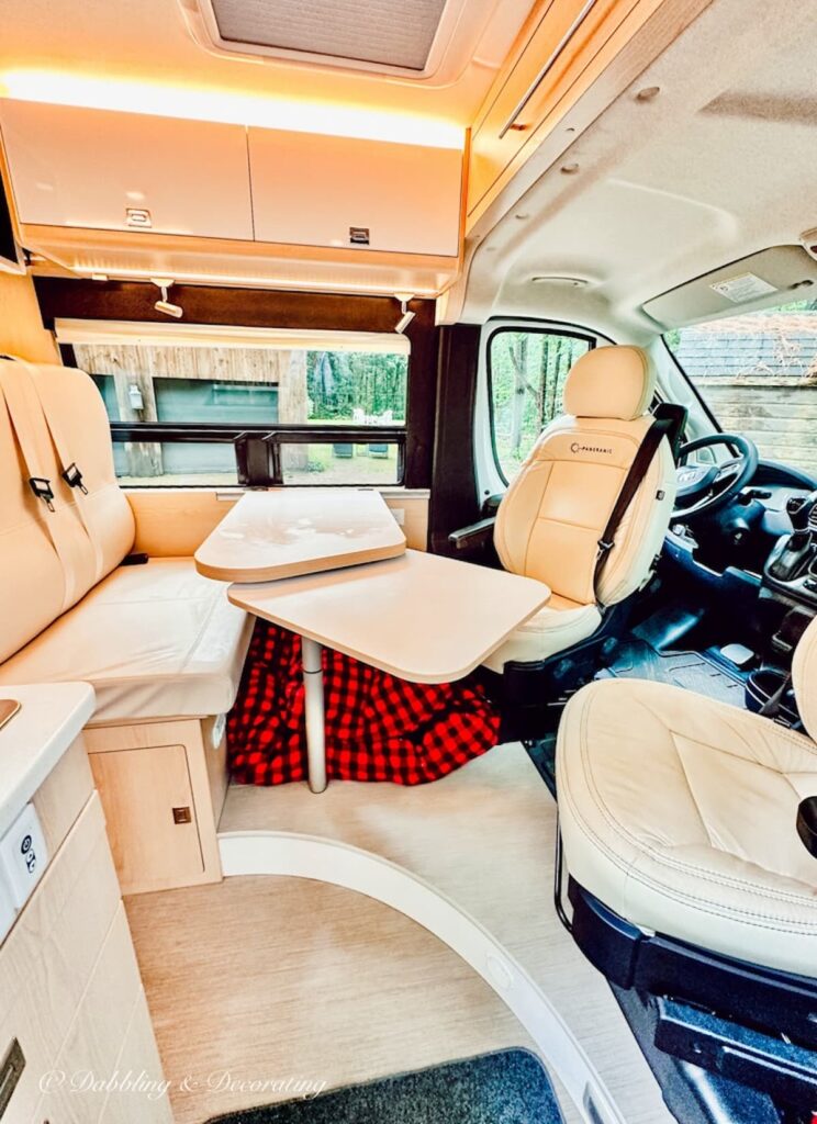 Inside Panoramic RV Interior with seating, tables in soft pastel.