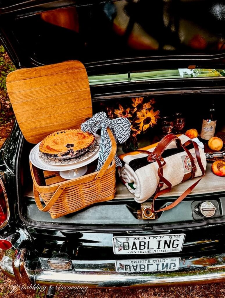 Pendleton wool blanket in vintage car trunk with leather strap in car picnic set up.