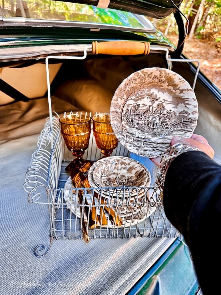 Brown and White vintage Transferware dishes in hand and basket Mount Vernon Amber Glassware in Vintage car trunk.