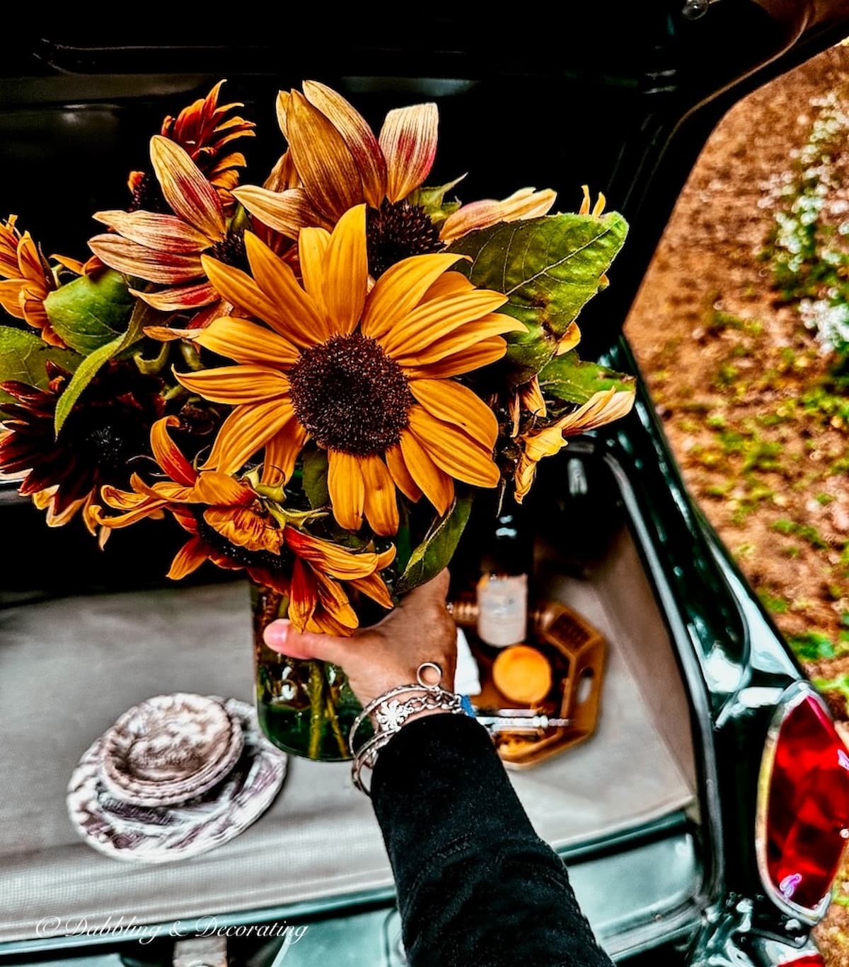 Sunflower bouquet in mason jar in hand for a car picnic.