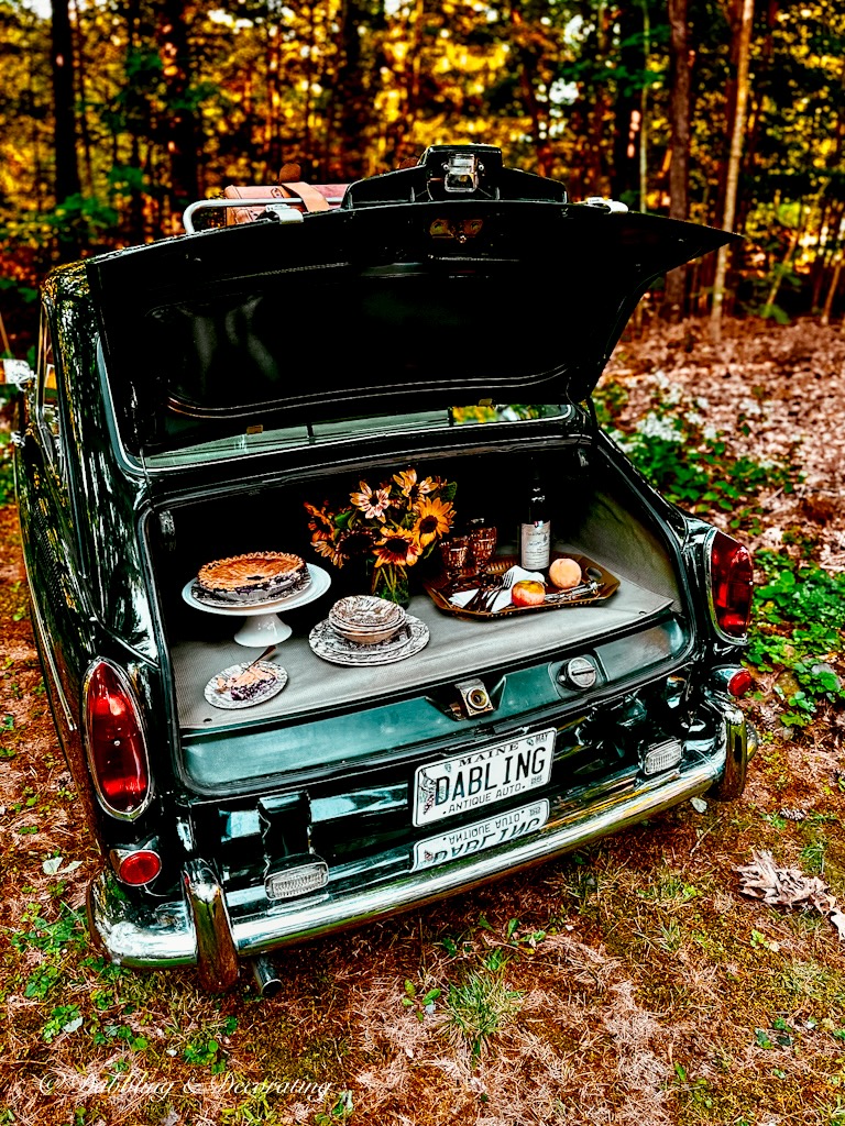 VW Fastback trunk open with car picnic display in the woods.