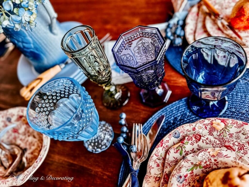 Several different colored glassware on fall tablescape.