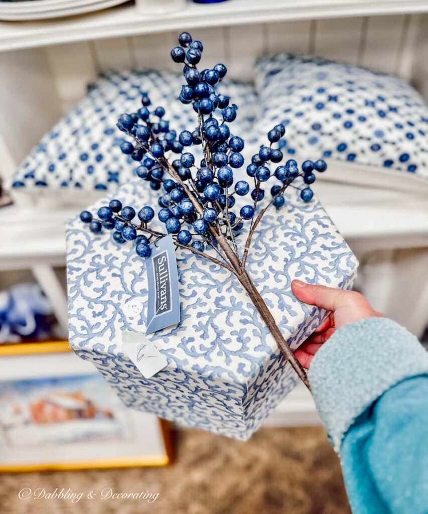 blueberry branch and blue and white hat box in hand at thrift shop.