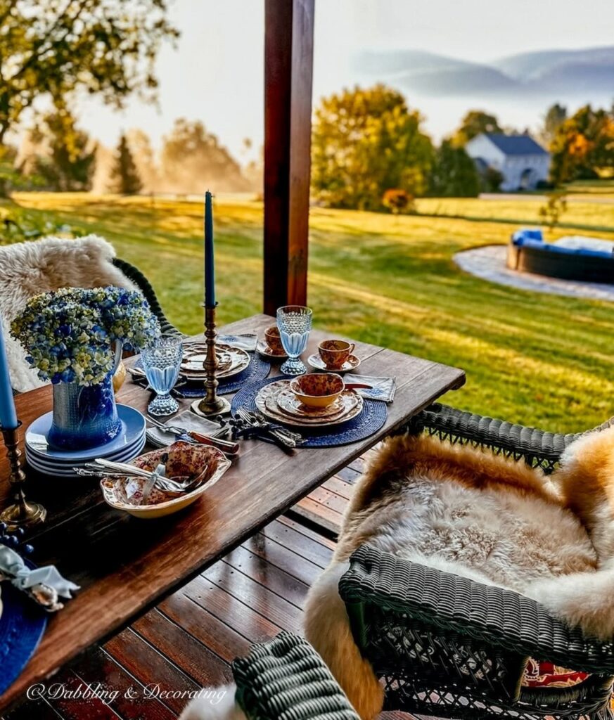 Fall tablescape with blue accents on porch overlooking fall foliage misty morning in Vermont Mountains.