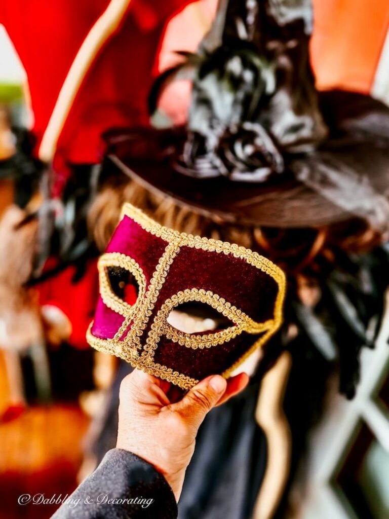 Purple masquerade mask in hand.