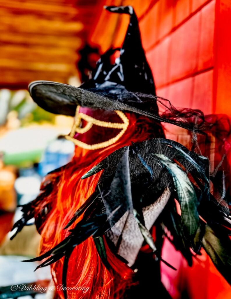 Witchy decor with masquerade mask, red hair, witches hat for Halloween.