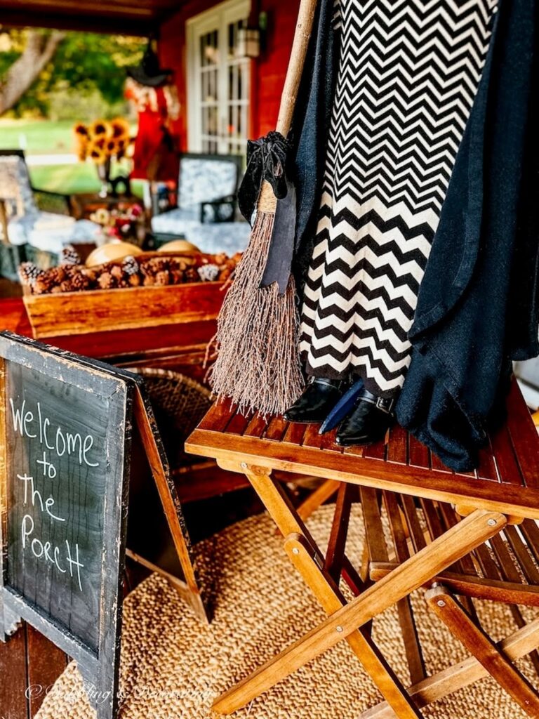 Black witch boots in witchy decor on front porch for Halloween.