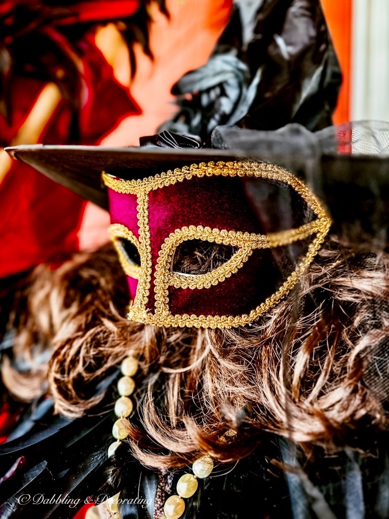 Purple masquerade mask on brown wig with witches hat for Halloween.