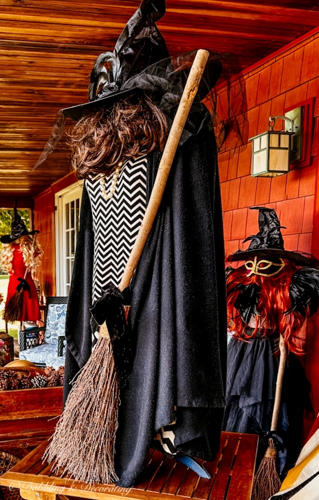 Witchy decor witch on front porch with witch's broom, hat dressed in black.