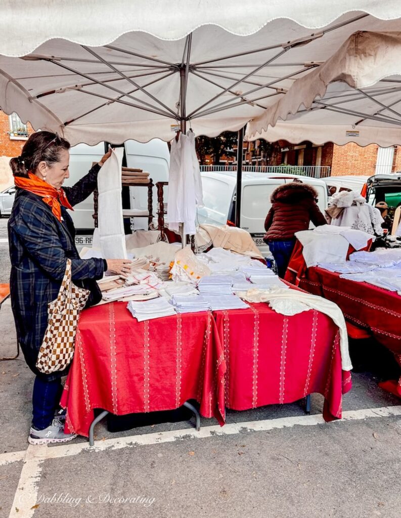 Woman shopping French linens at a flea market antiquing in Paris.