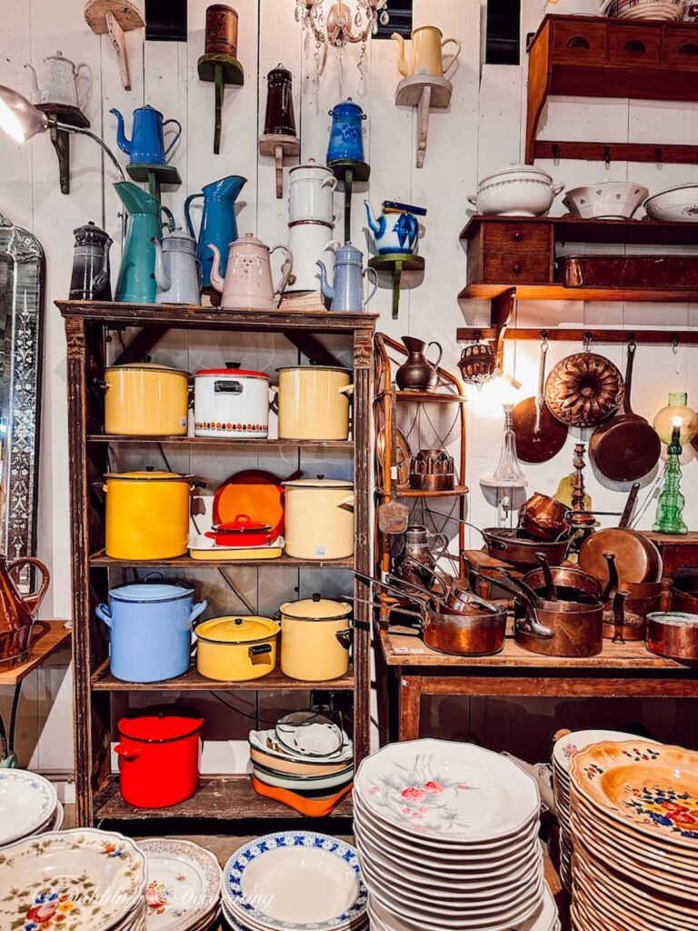 Colorful vintage kitchen pots on rack in antique shop.