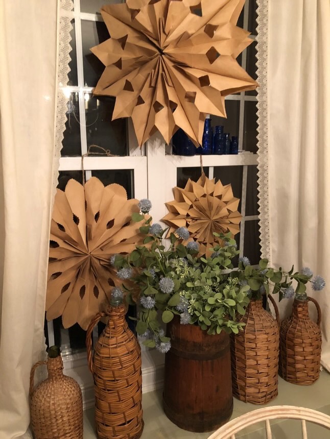 vintage Demijohn collection on winter styled windowsill with paper snowflakes.