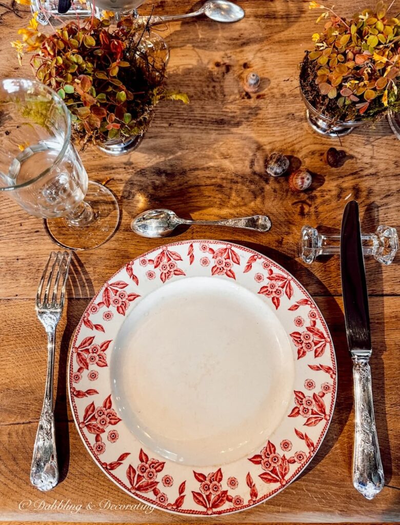 Place setting with red dish and silver and crystal tableware.