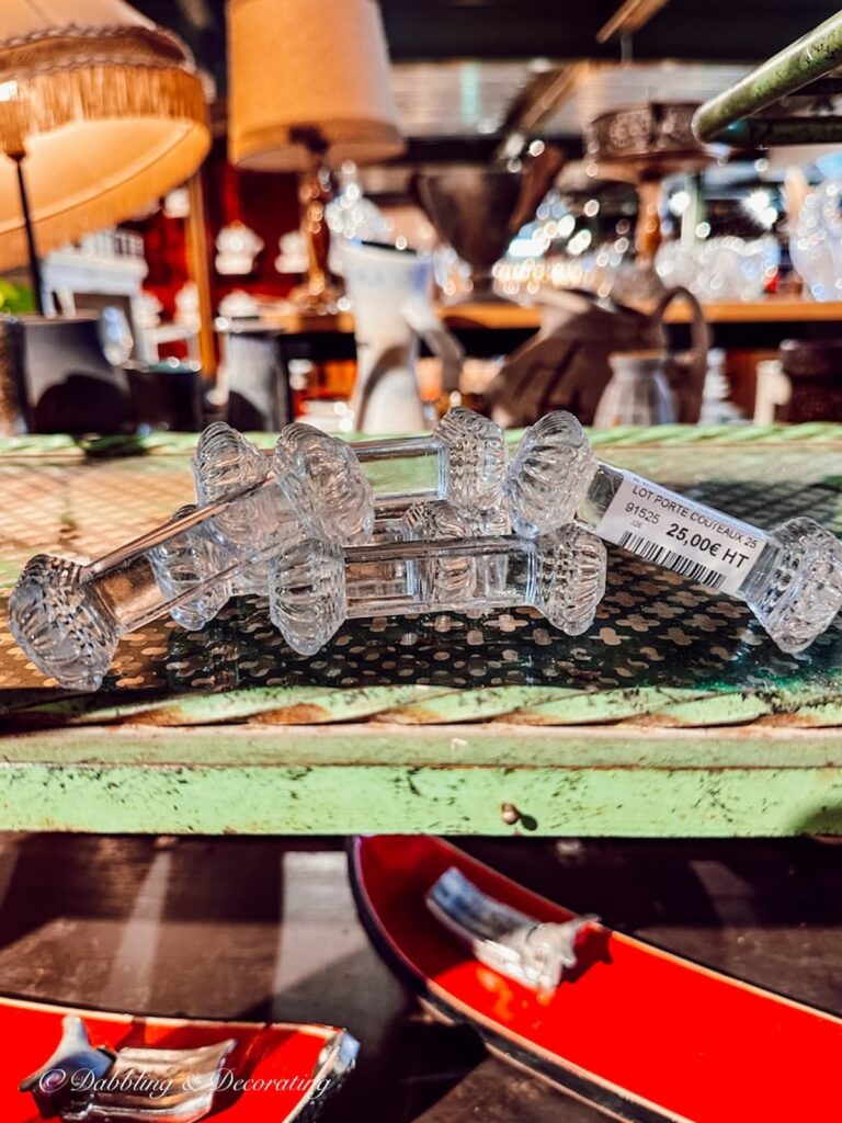 Set of six crystal knife rests on vintage haul rack in antique store.