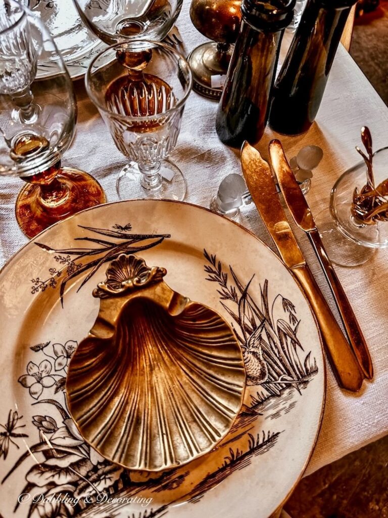 Gold flatware on brown table setting with knife rest in France.