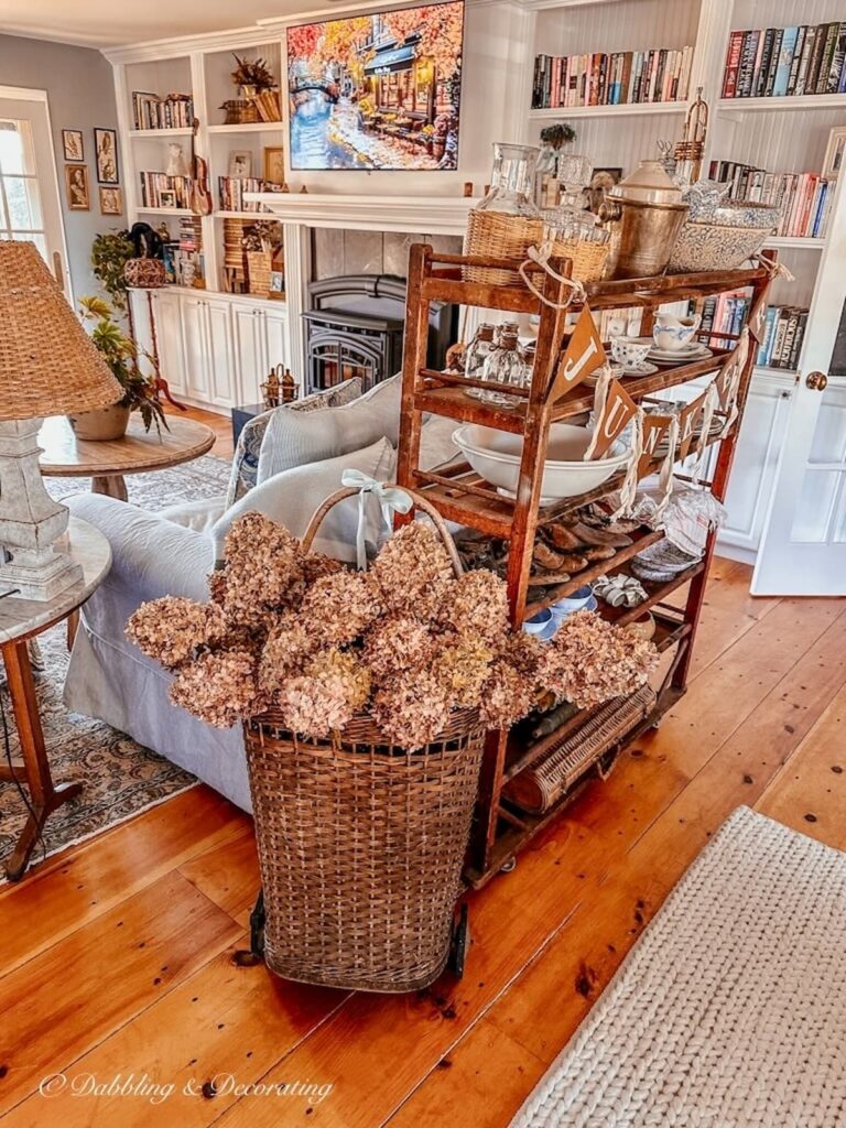 Basket of fall hydrangeas leaning on a vintage cobbler rack in living room space with vintage finds.