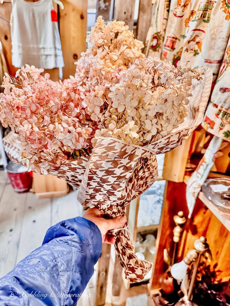 Fall hydrangeas with pink hues bundled in brown and pink wrapping paper in hand.