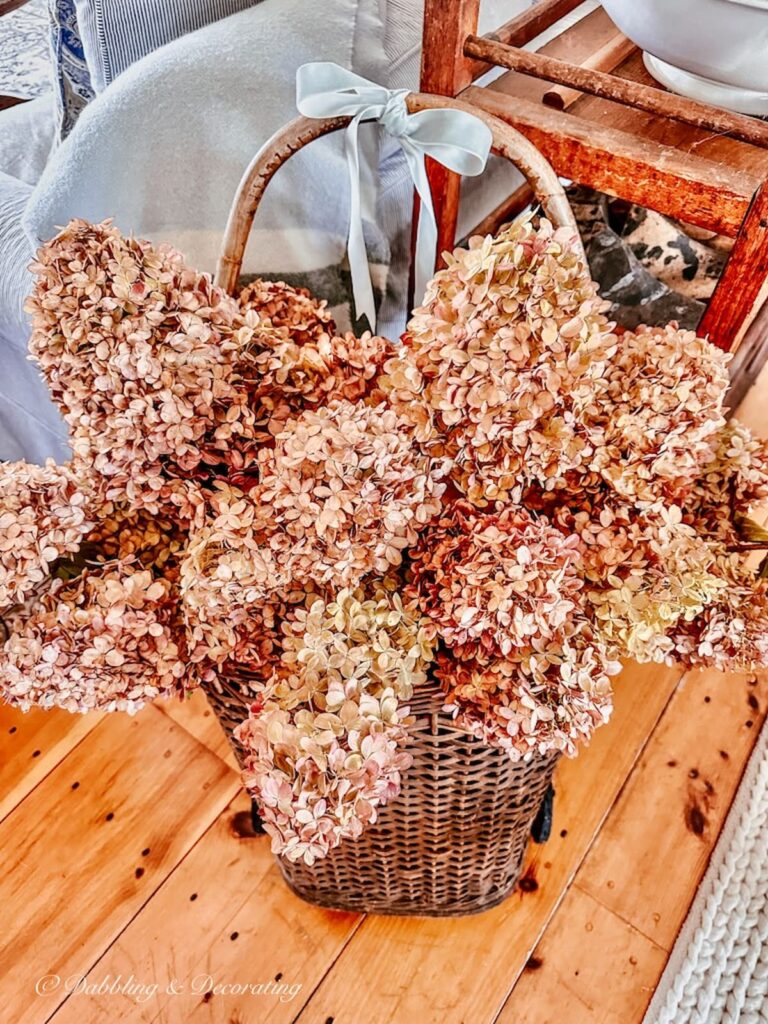 Basket of pink fall hydrangeas with blue velvet bow in vintage home decor.