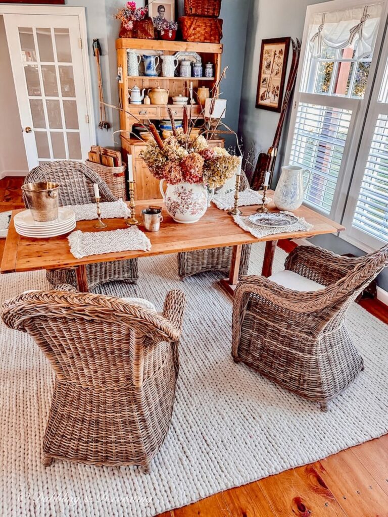 Vintage Style Dining Room decorated for fall with fall hydrangeas in transferware pitcher with wicker chairs and vintage pine cupboard.