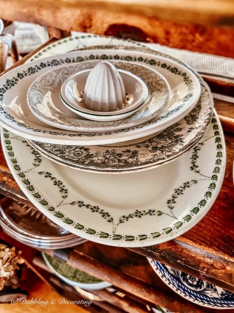 Stack of green and white platters and dishes on shelf.