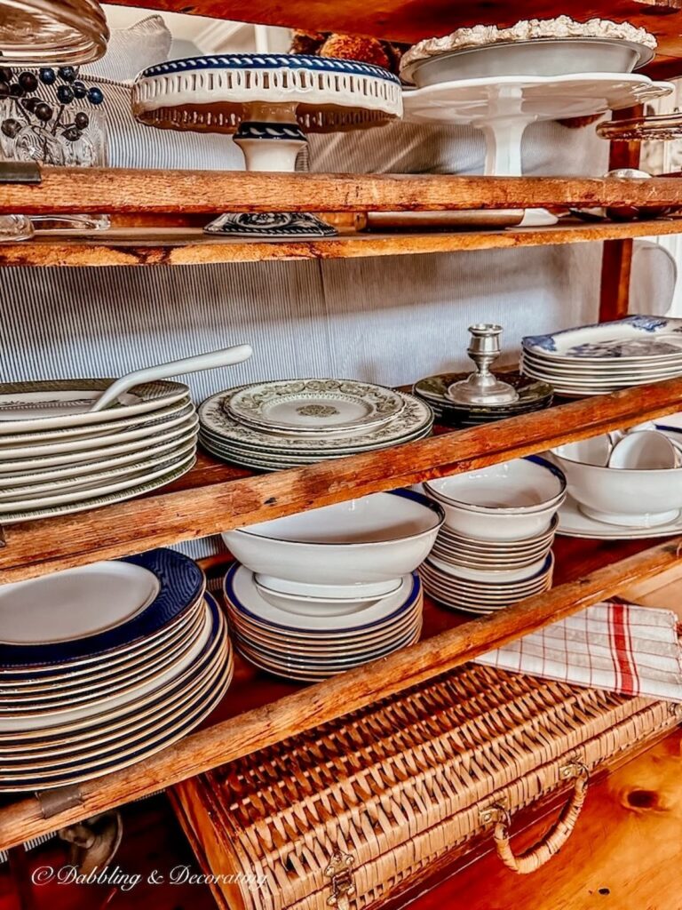 Stacked vintage dishes on an antique cobbler wooden rack.