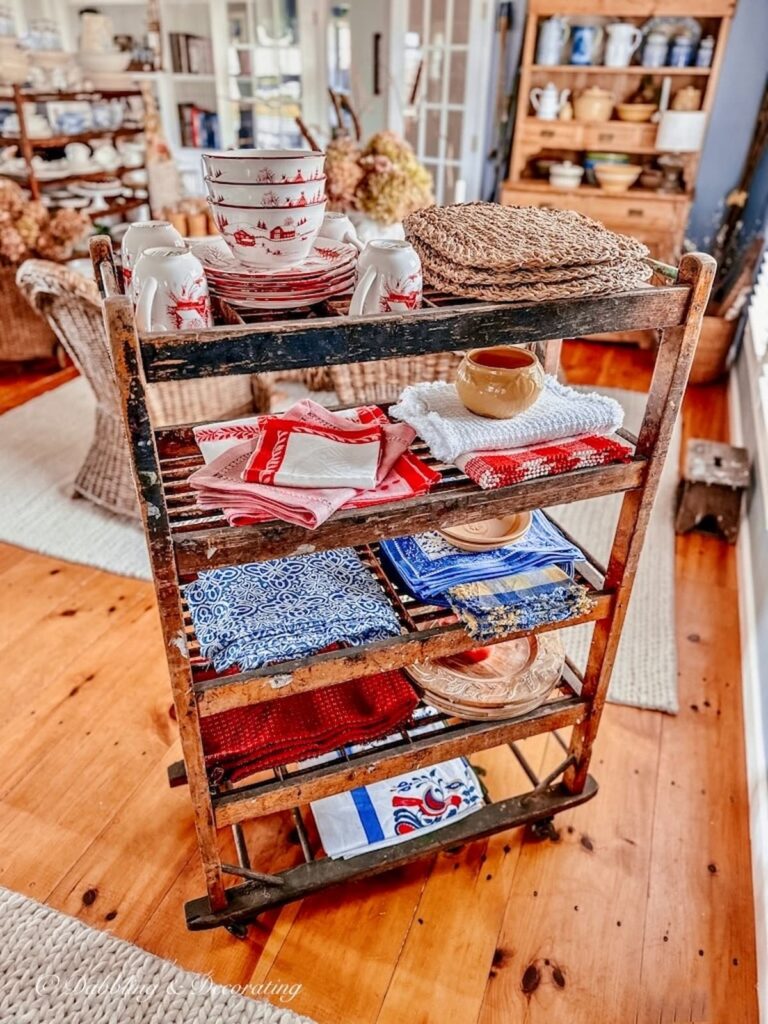 Antique style dining room with fall centerpiece and vintage cobbler rack with dining room linens as a room divider in open floor plan space.